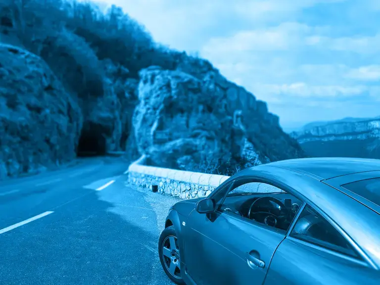 Teilansicht eines Audis auf einer Bergstraße von hinten