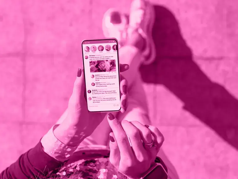 Eine Frau, die ein Handy hält auf dem ein Social Media Kanal zu sehen ist.