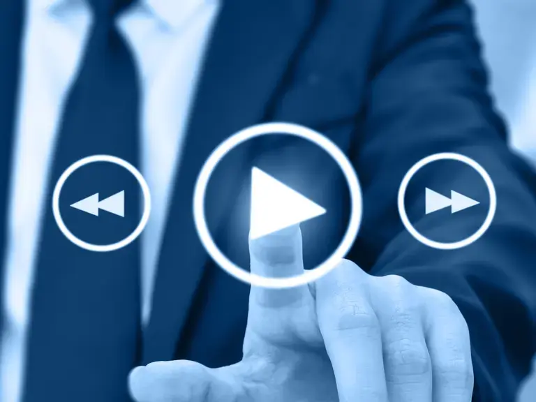 Ein Mann im Anzug der von hinten auf das Startsymbol einer digitalen Anzeige tippt