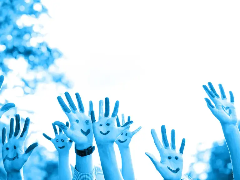 Kinderhände mit Smiley Gesichtern, die in die Luft gestreckt werden