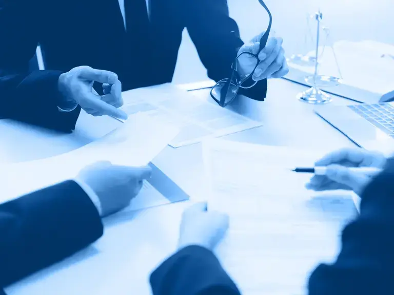 Ein Vertrag der auf einem Tisch liegt und Hände die darauf zeigen