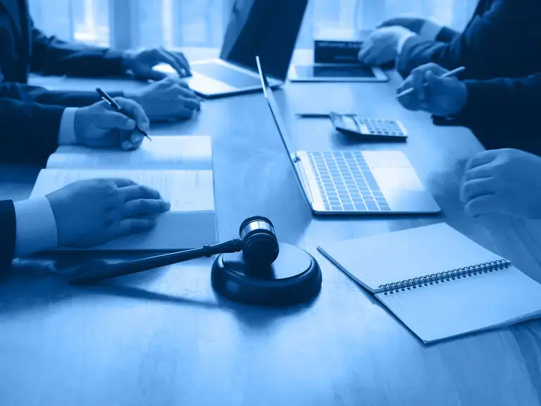 Ein Besprechungstisch auf dem Hände und ein Laptop zu sehen sind