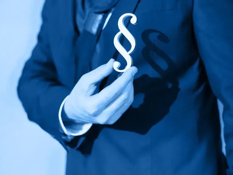 Ein § Symbol, das vor die Brust eines Anwalts gehalten wird