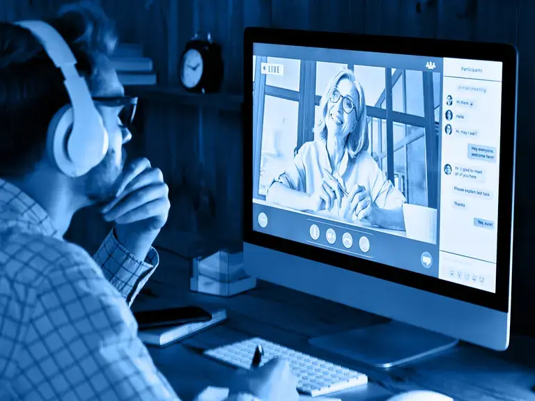 Ein Mann der vor einem Bildschirm sitzt und ein Webinar anschaut