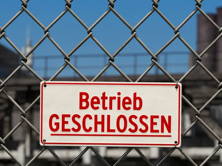 Ein Schild auf dem Betrieb geschlossen steht und an einem Maschendrahtzaun befestigt ist