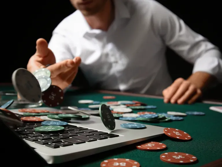 Ein Mann der Jetons auf einen Tisch mit einem Laptop wirft