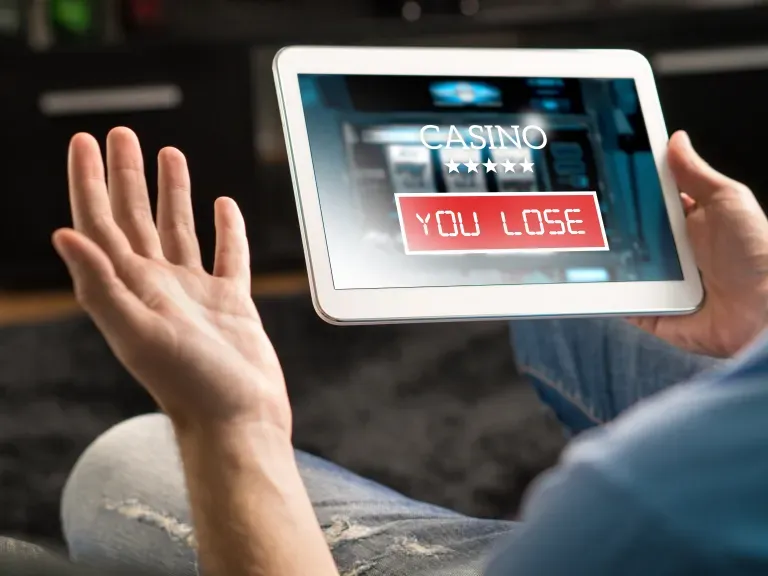 Hände die ein Tablet halten auf dem Steht Casino you lose