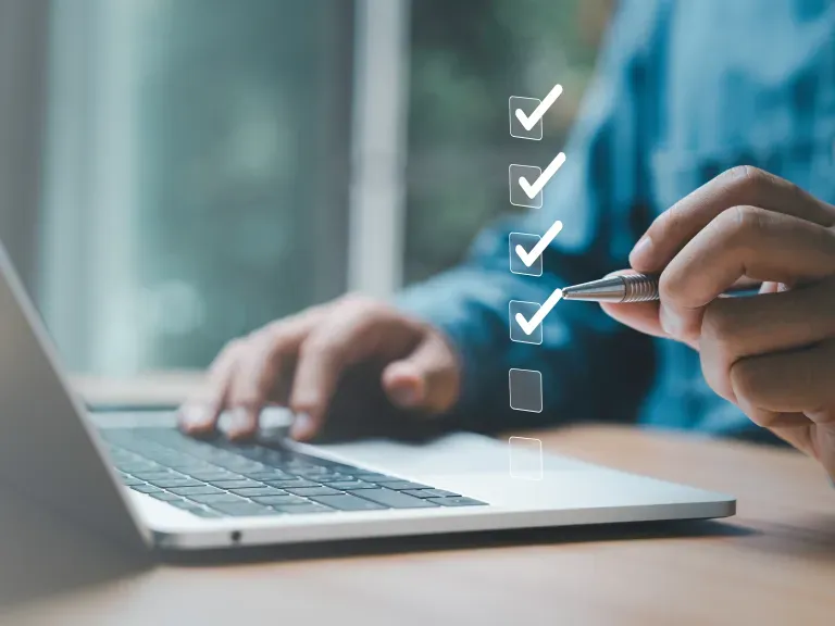 Im Hintergrund ein Laptop. Im Vordergrund schweben Kästchen mit Haken untereinander