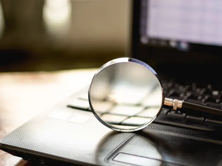 Eine Lupe die auf einem Laptop liegt