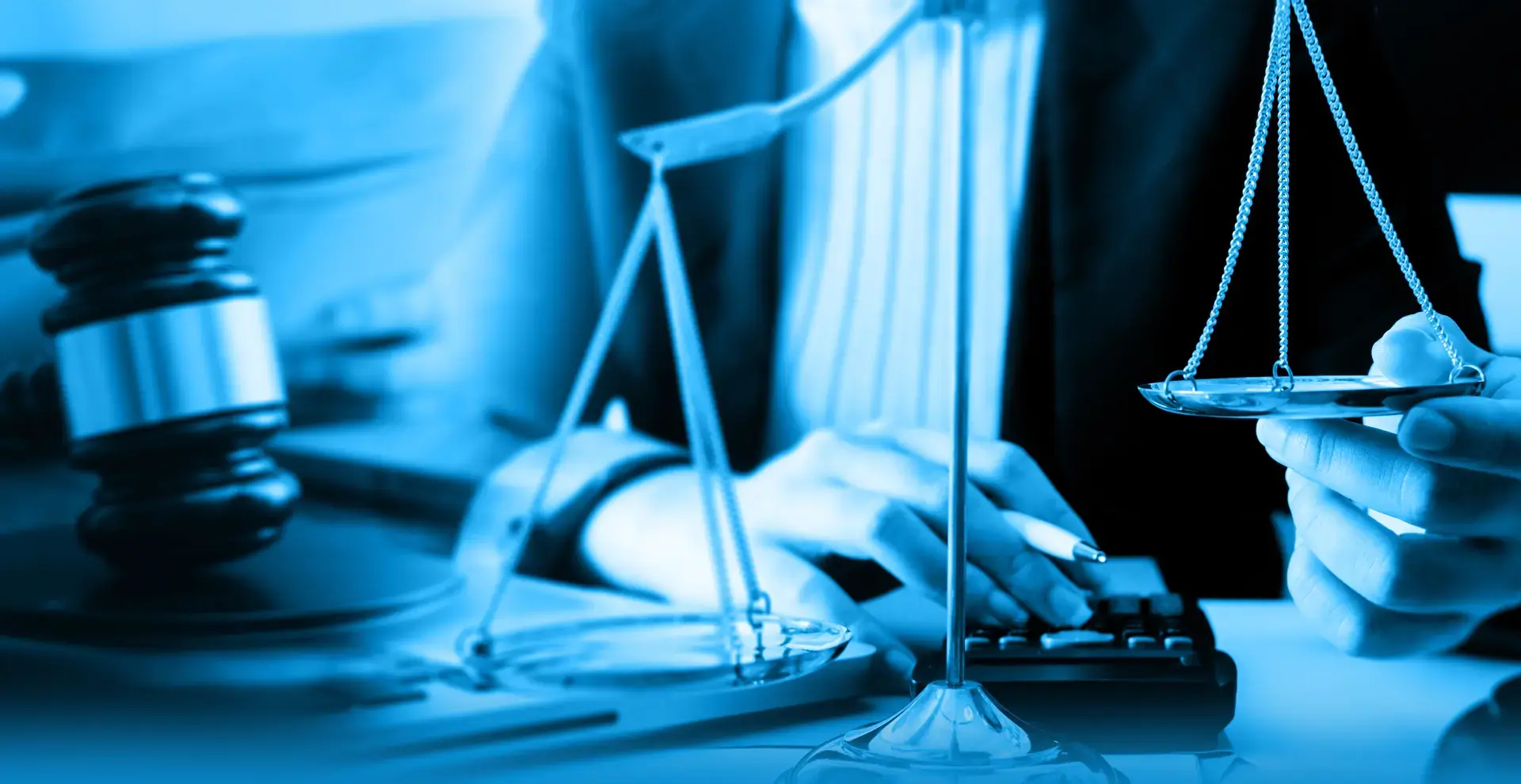 Im Vordergrund eine Waage und ein Richterhammer - im Hintergrund eine Frau die mit der einen Hand einen Taschenrechner bedient und mit der anderen eine Schale der Waage hält