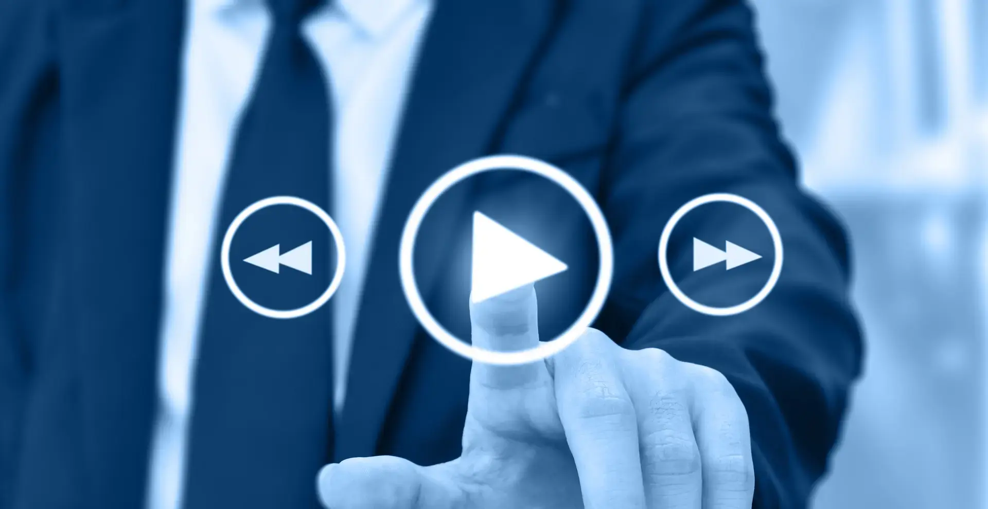 Ein Mann im Anzug der von hinten auf das Startsymbol einer digitalen Anzeige tippt