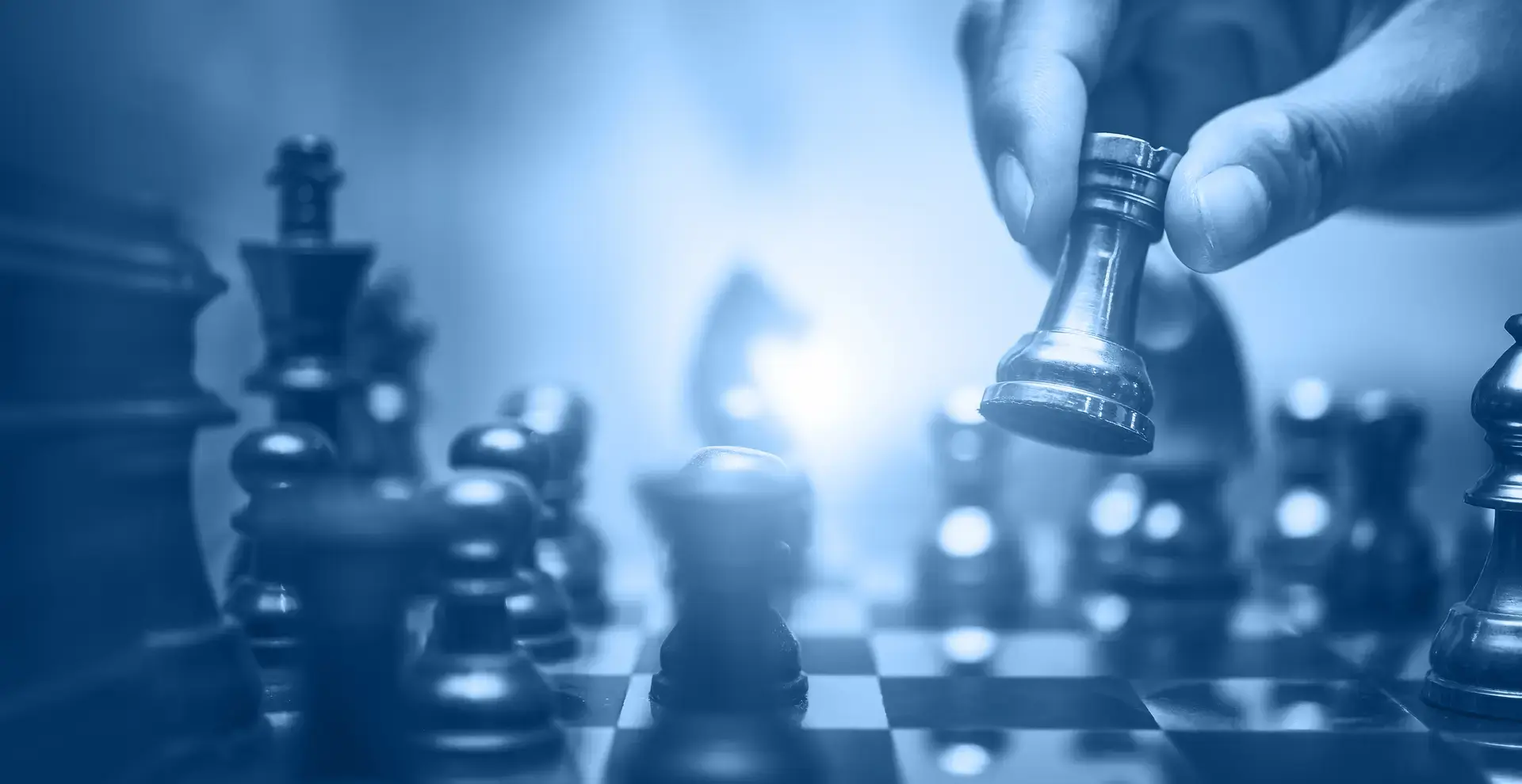 Schachfiguren - eine wird von einer Hand hochgehoben