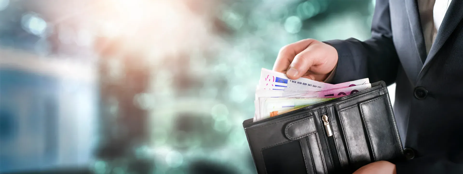 Hand, die Scheine aus einem Geldbeutel nimmt.