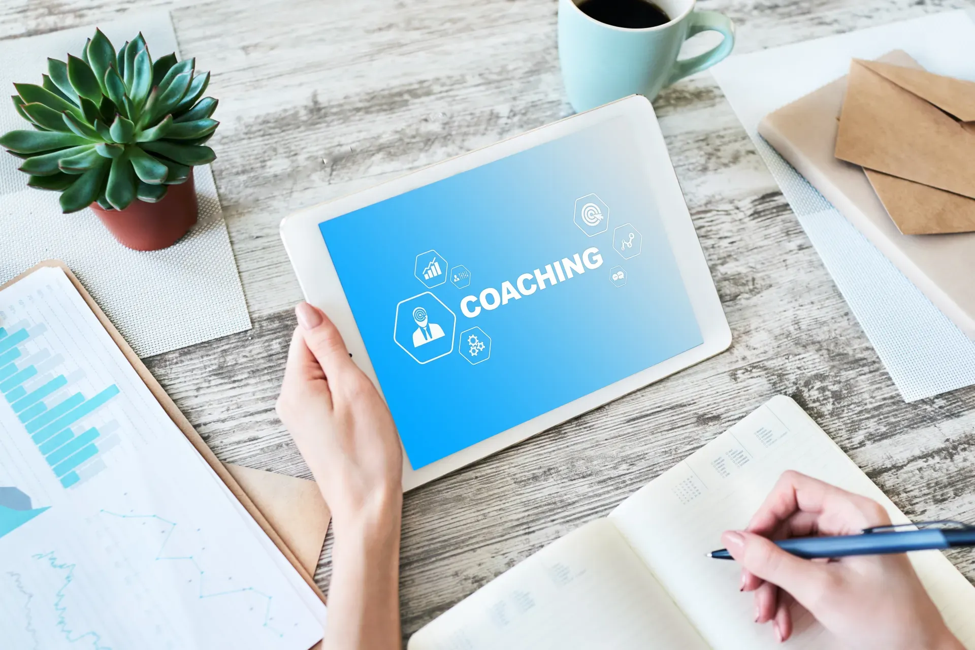 Im Zentrum ein Tablet auf dem Coaching steht. Im Umfeld ein Schreibtisch mi Utensilien