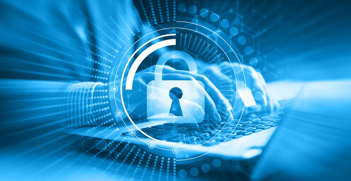 Ein digitales Bild im Hintergrund Hände, die ein Laptop bedienen, im Vordergrund ein digitales Schloss