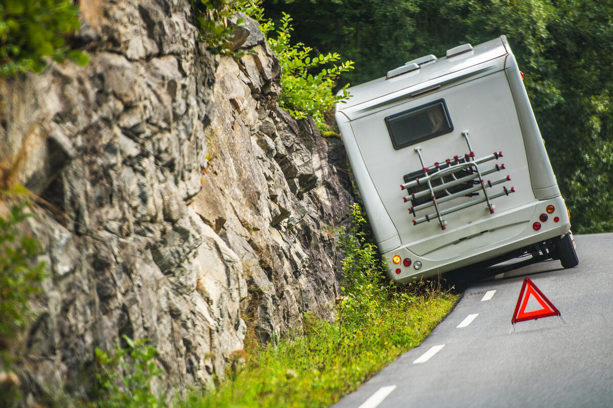 Ein Wohnmobil das auf der Straßenseite seht, davor das Warnzeichenschild