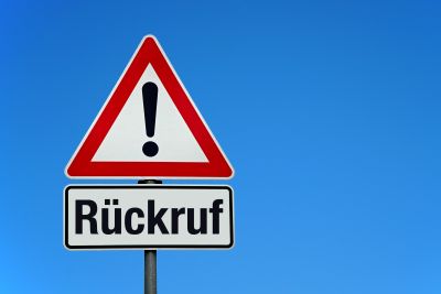 Ein dreieckiges Verkehrsschild mit einem Ausrufzeichen und darunter steht Rückruf