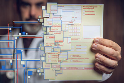 Mann hält seine Arbeitsunfähigkeitsbescheinigung für ein Gutachten über Berufsunfähigkeit in die Höhe.