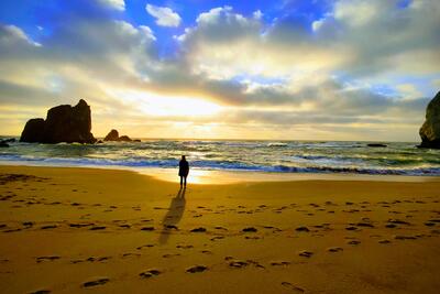 Frau am Strand beoachtet einen Sonnenuntergang