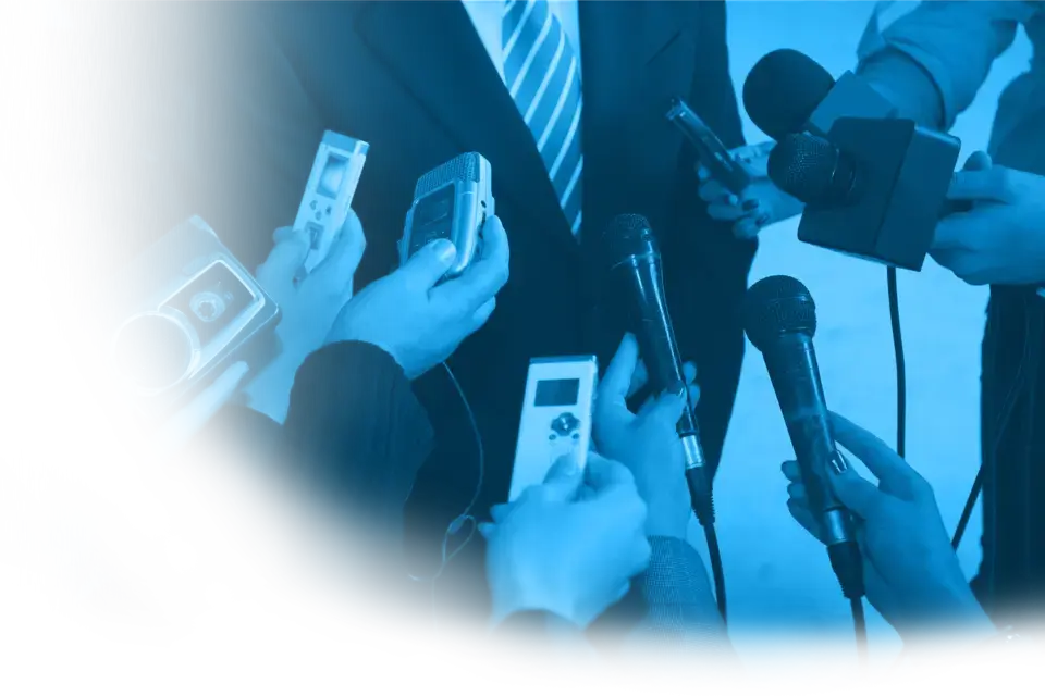 Mehrere Mikrofone, die einem Mann im Anzug entgegen gehalten werden.