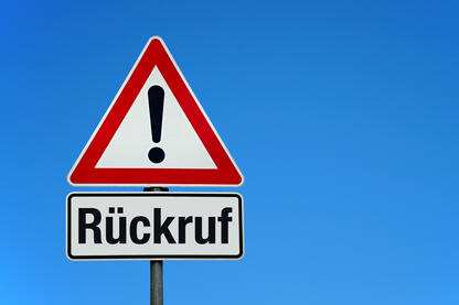 Ein dreieckiges Verkehrsschild mit einem Ausrufzeichen und darunter steht Rückruf