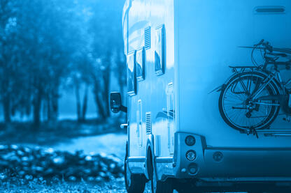 Heckansicht eines Wohnmobils, das über eine Waldstraße fährt.