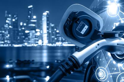 Ein Ladevorgang für ein E-Auto mit digitalen Symbolen im Hintergrund eine Skyline